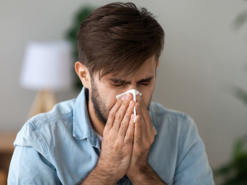 man sneezes out allergens