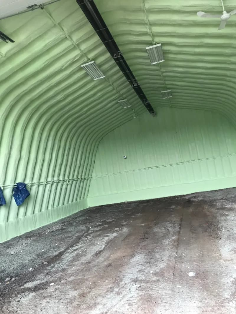 Quonset-style building interior with spray foam Curved metal building interior fully lined with green spray foam and a ceiling fan