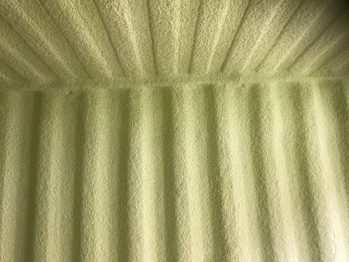 Curved ceiling spray foam texture Close-up of ribbed green spray foam lining a curved building ceiling
