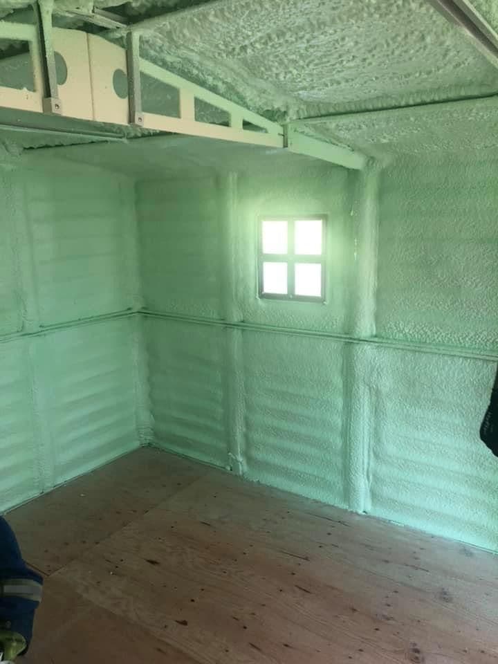 Insulated interior room with a window Interior room with green spray foam on walls and rafters near a window